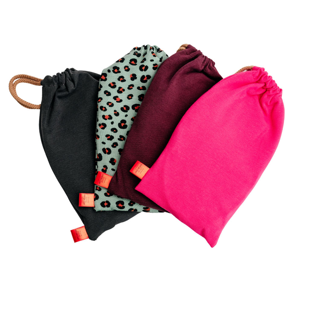 Four drawstring bags in black, leopard print, maroon, and pink are arranged side by side, made from organic jersey cotton. These versatile bags are perfect for holding the Reusable Face Wipes - Pack of 7 + Bag - Small by Good Wash Day.