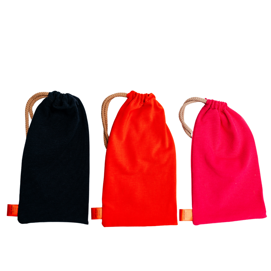 From Good Wash Day, the Large Drawstring Bag - Buy 2 Get 1 Free offer includes three eco-friendly fabric pouches in black, orange, and pink. Each pouch features a beige drawstring and is handmade in the UK from organic jersey fabric.