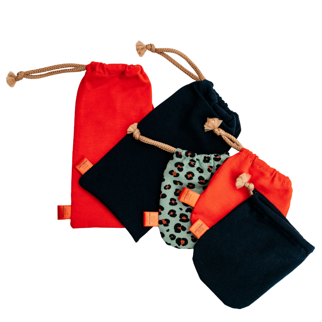 Five small drawstring bags from Good Wash Day, handmade in the UK from organic jersey fabric, in varying sizes and colors including red, black, and green leopard print, arranged in a scattered formation. Buy 2 Get 1 Free.