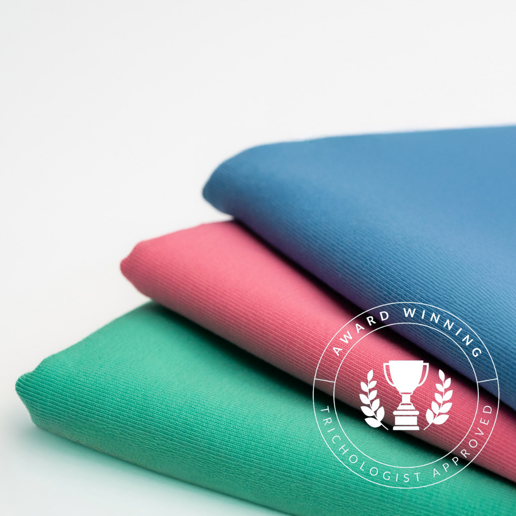 Introducing The Pastels by Good Wash Day: a set of three folded fabrics in beautiful blue, pink, and green hues. Each piece is topped with an "Award Winning Trichologist Approved" emblem. Crafted from organic jersey cotton towel, these handmade products from the UK are perfect for those with sensitive skin.